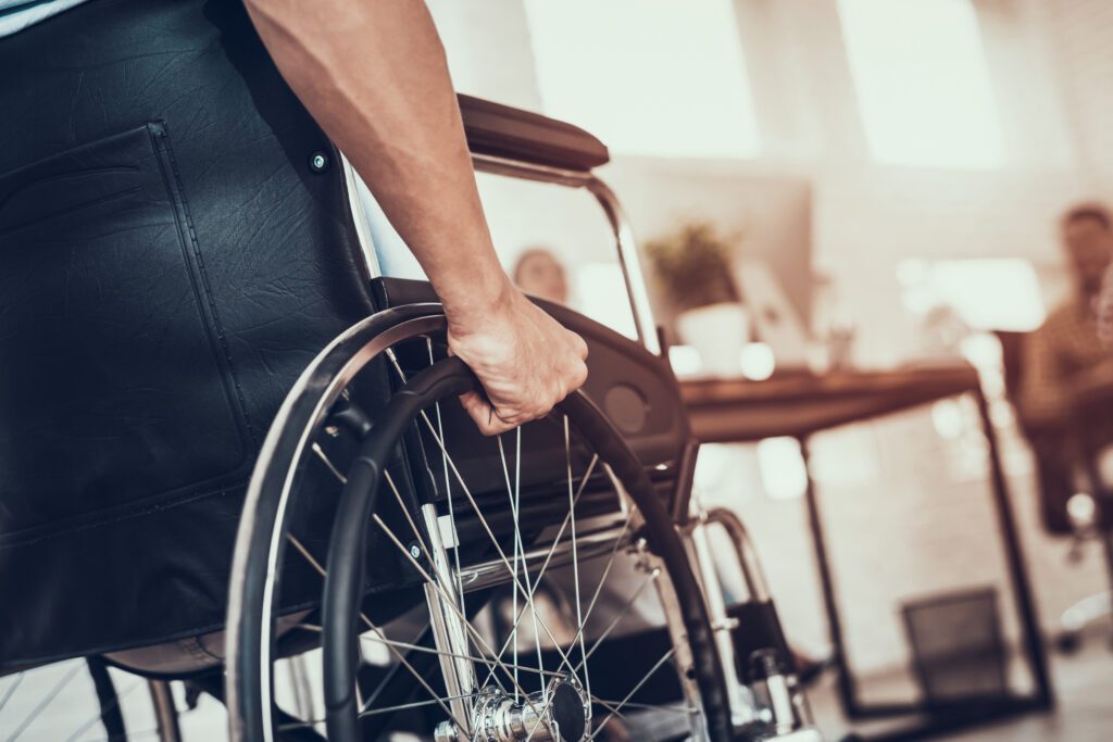 Man using a wheelchair working at a desk in an office setting.