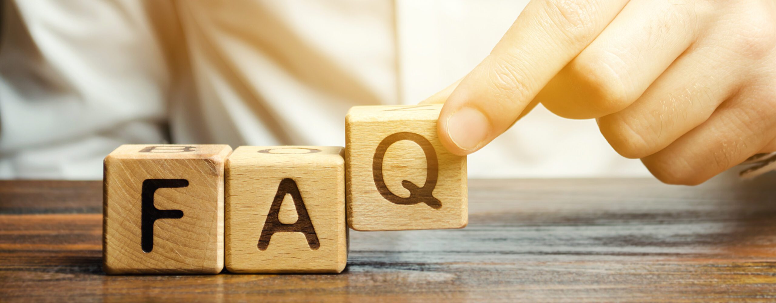 Wooden blocks spelling FAQ on a desk.