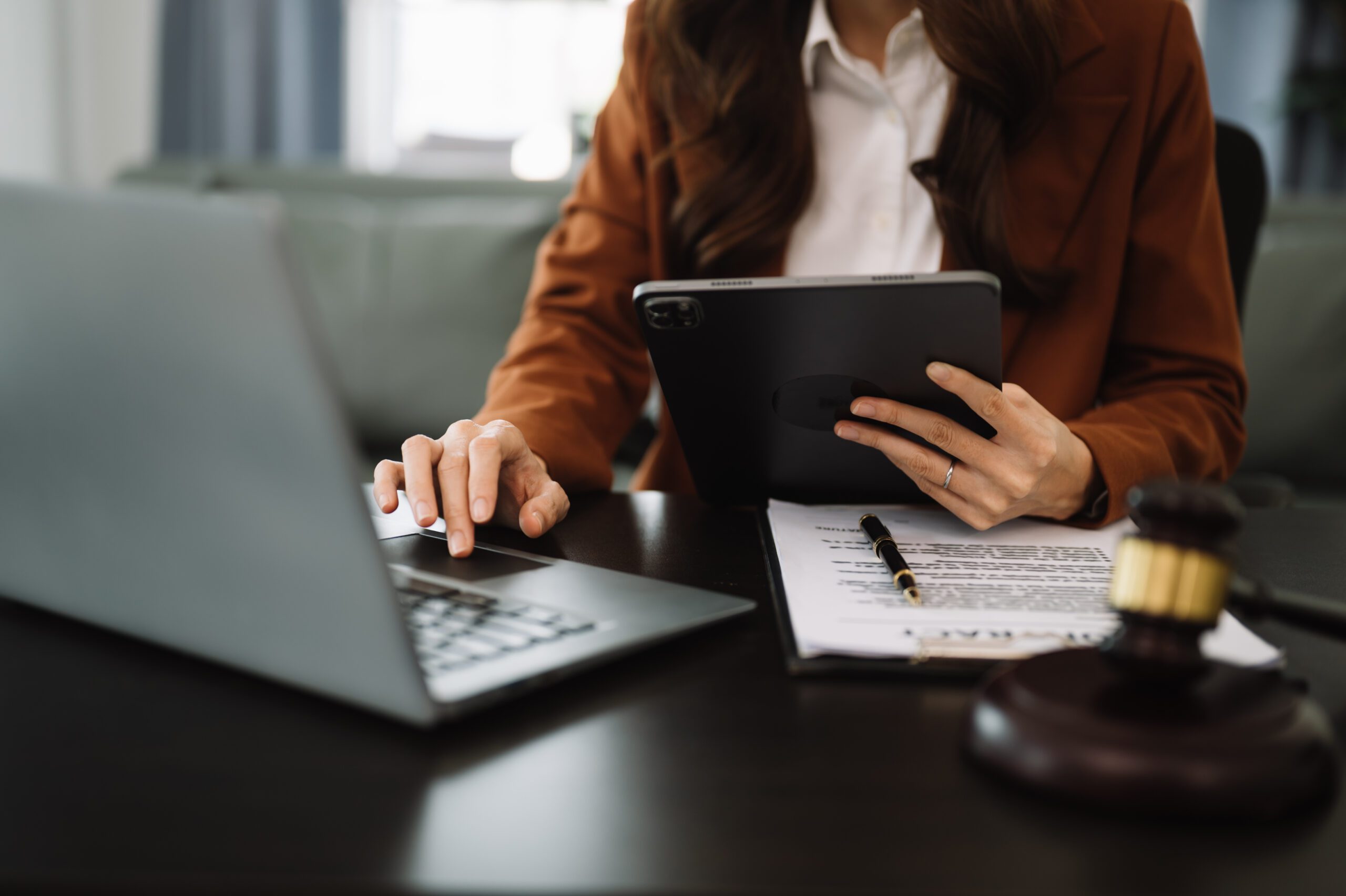Person working on a laptop and tablet with papers on a desk