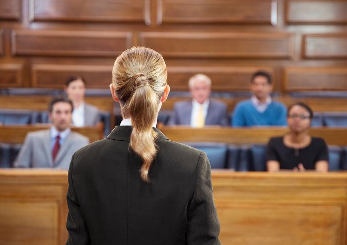An attorney addresses a seated jury panel during a courtroom proceeding.