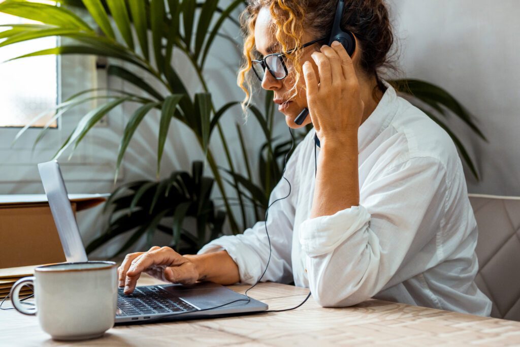 Woman using a computer and headset for a video call.