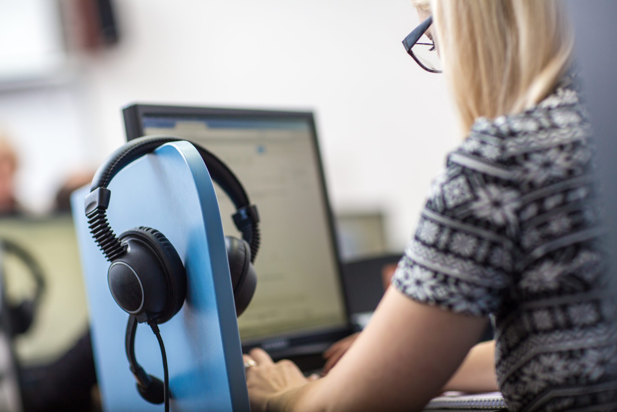 Court interpreter at a workstation with headphones, microphone, and laptop.