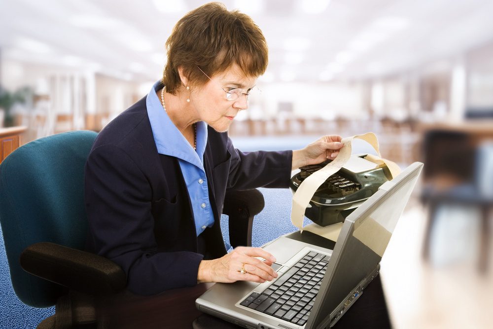 Person typing notes on a laptop during a meeting to document proceedings.