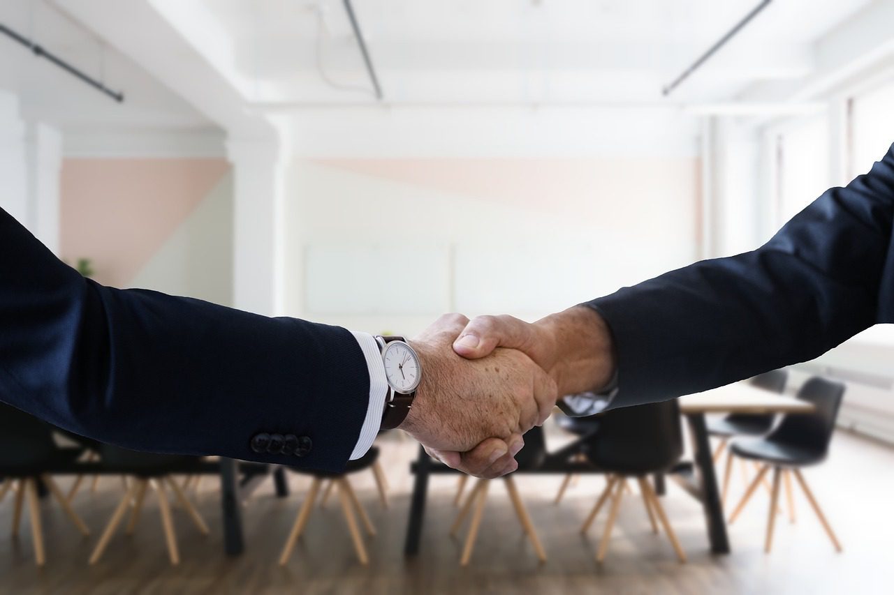 Two people shaking hands during a job interview.