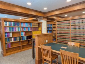 A quiet study table with three chairs surrounded by legal reference book shelves inside the library.